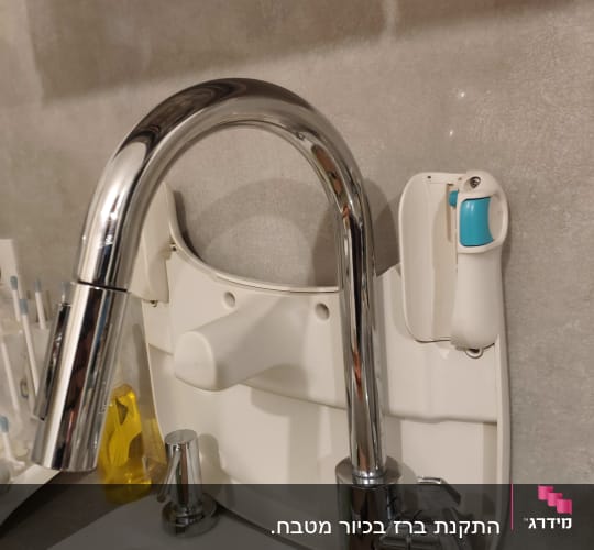 ברז נירוסטה עם ידית סבון ליד כיור